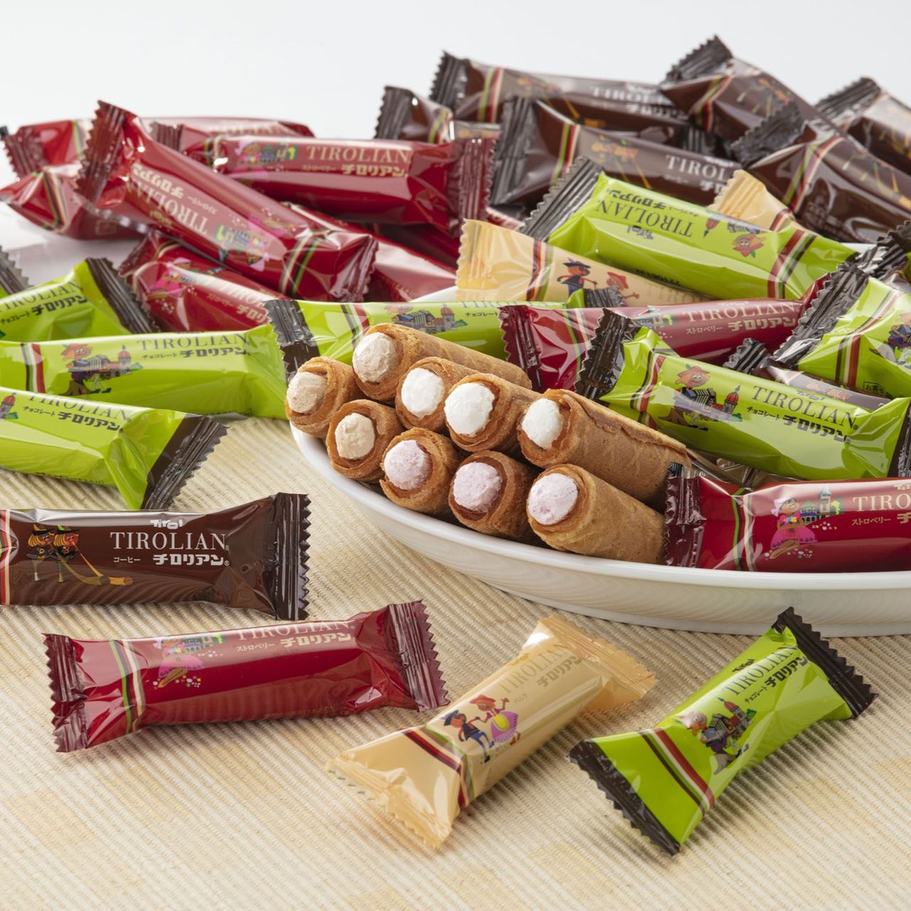 A plate of assorted Tirolian candy wrappers in red, green, brown, and yellow, with rolled wafer cookies at the center.