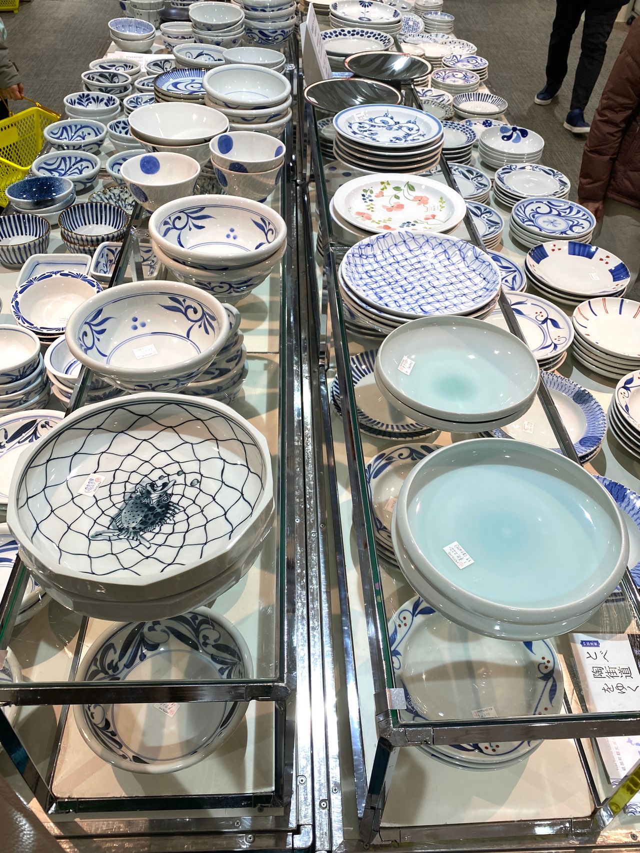 Various ceramic bowls with blue patterns displayed on shelves at a store, featuring floral and geometric designs.