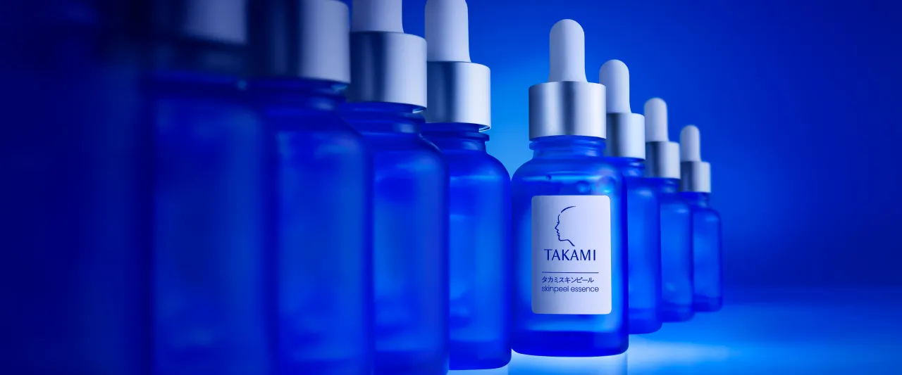 Blue bottles of Takami skincare products lined up against a blue background.