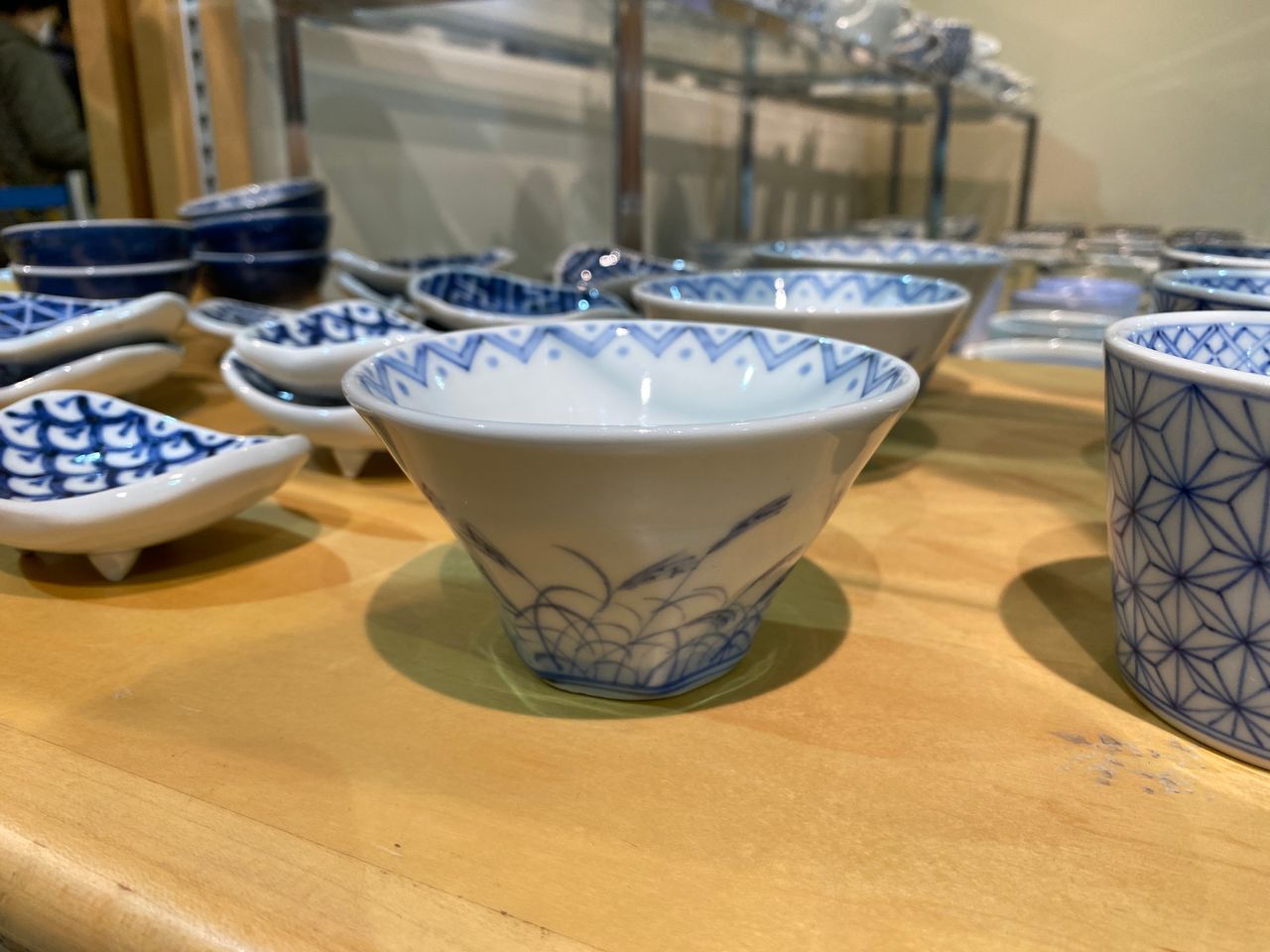 Assorted blue and white ceramic bowls with intricate patterns displayed on a wooden shelf.