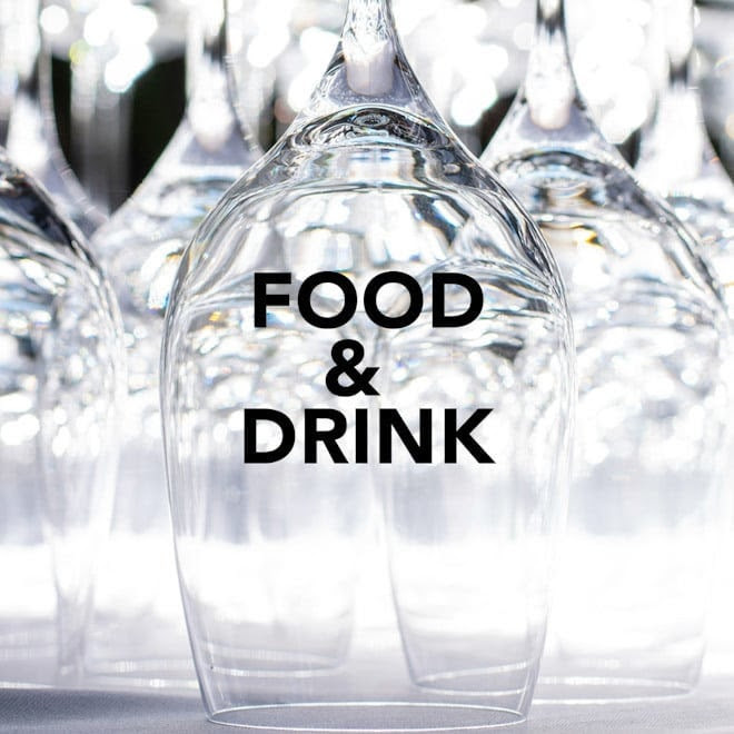 Upside-down wine glasses with "FOOD & DRINK" text on one glass, reflecting light.